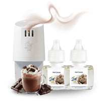 White Scent Fill plug-in diffuser releasing a soft cocoa-colored fragrance mist beside two Hot Cocoa refill bottles, with a mug of hot cocoa topped with whipped cream and chocolate pieces on a light background.