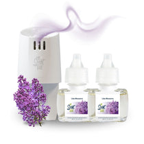 White Scent Fill plug-in diffuser releasing a soft purple fragrance mist beside two Lilac Blossoms refill bottles, with a cluster of lilac flowers on a light background.